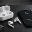 AirPods neben Ladecase und Smartphone mit Bluetooth-Kopplung